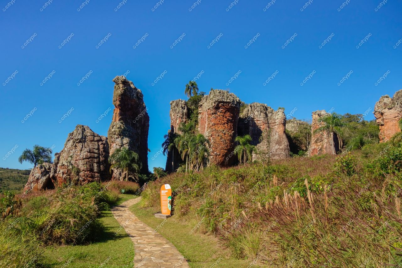 Ponta Grossa, Paraná formação rochosa com pilares naturais sob céu azul e caminho de pedra entre vegetação verdejante