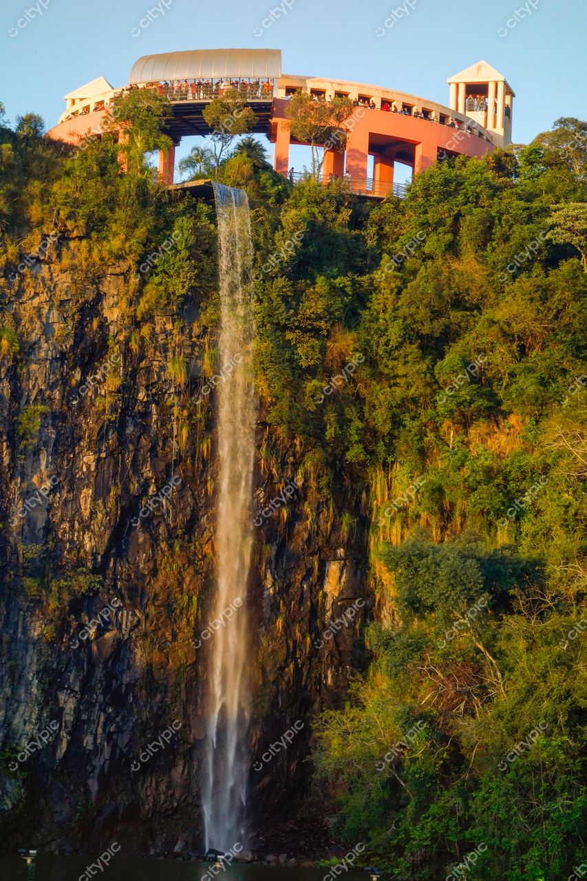 Curitiba, Paraná, cachoeira em formação rochosa com deck de observação ao pôr do sol e vegetação abundante