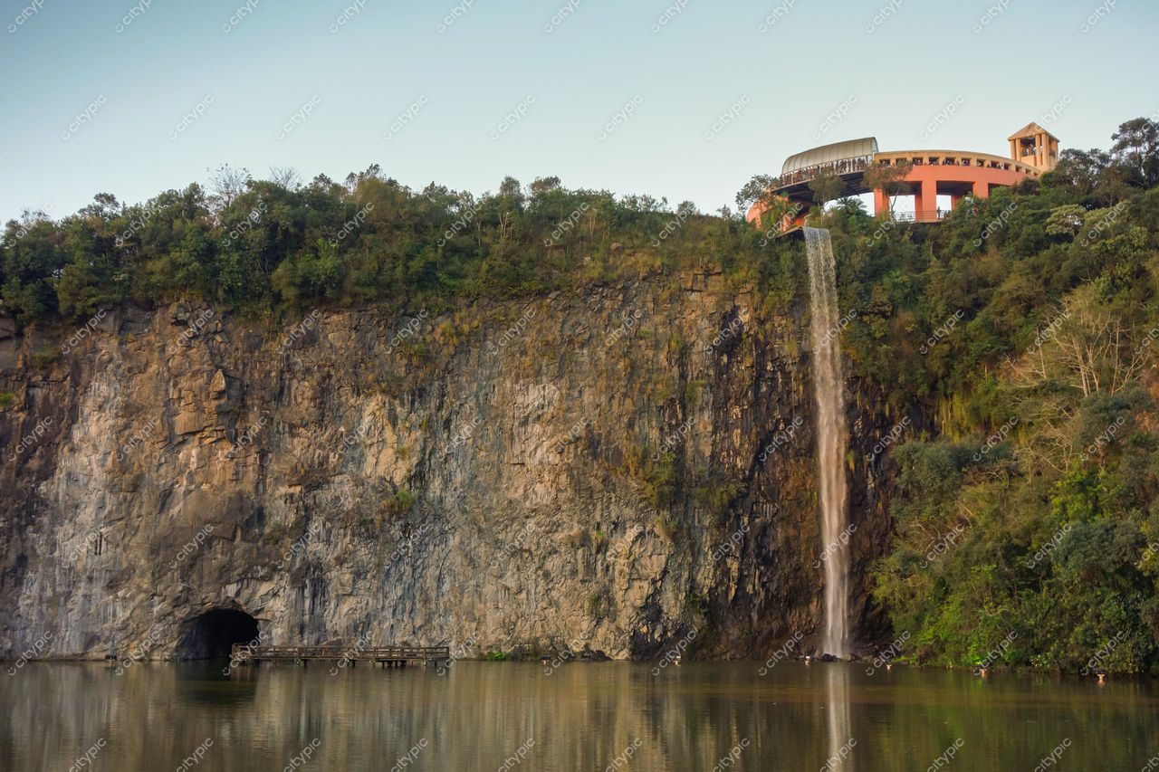 Curitiba, Paraná, queda d’água em rocha íngreme com estrutura arquitetônica e lago refletindo o pôr do sol
