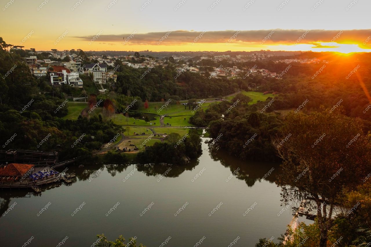 Curitiba, Paraná vista panorâmica ao pôr do sol com rio tranquilo, vegetação, colinas e edificações residenciais