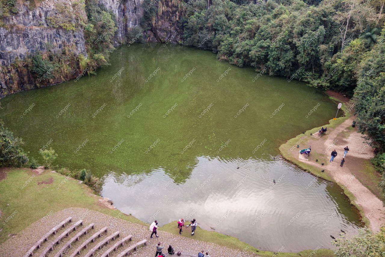 Curitiba, Paraná vista panorâmica de lago com vegetação densa e pessoas caminhando em dia nublado