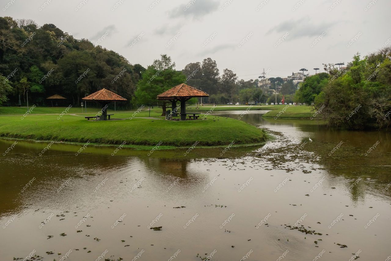 Curitiba, Paraná, sereno lago com gazebos de telhado inclinado e vegetação densa sob iluminação suave em dia nublado