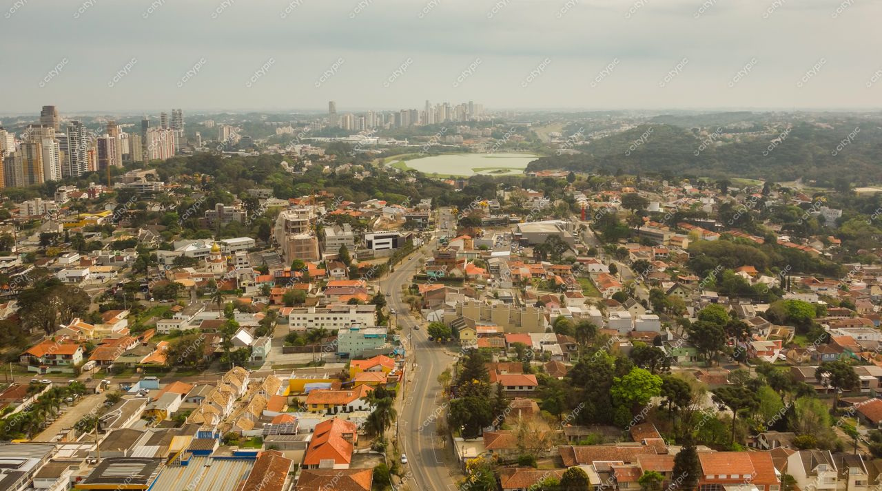 Curitiba, Paraná vista aérea com telhados coloridos, edifícios altos e lago em tarde nublada com vegetação