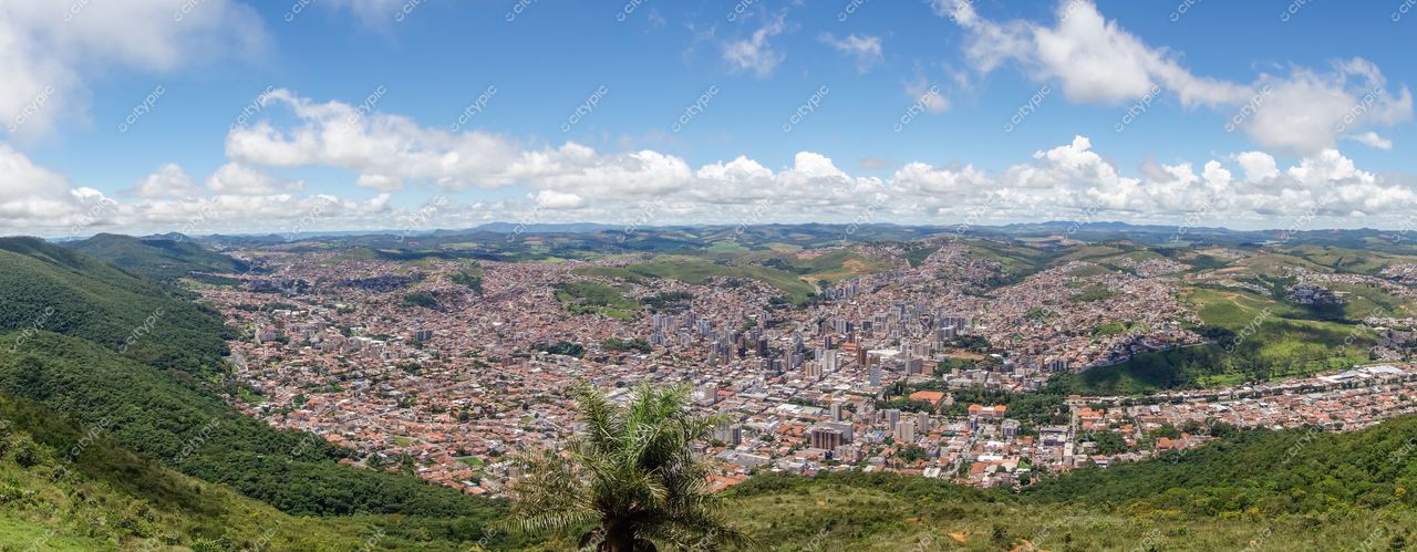 Poços de Caldas, Minas Gerais com vista panorâmica da cidade e montanhas verdes sob céu azul e nuvens brancas