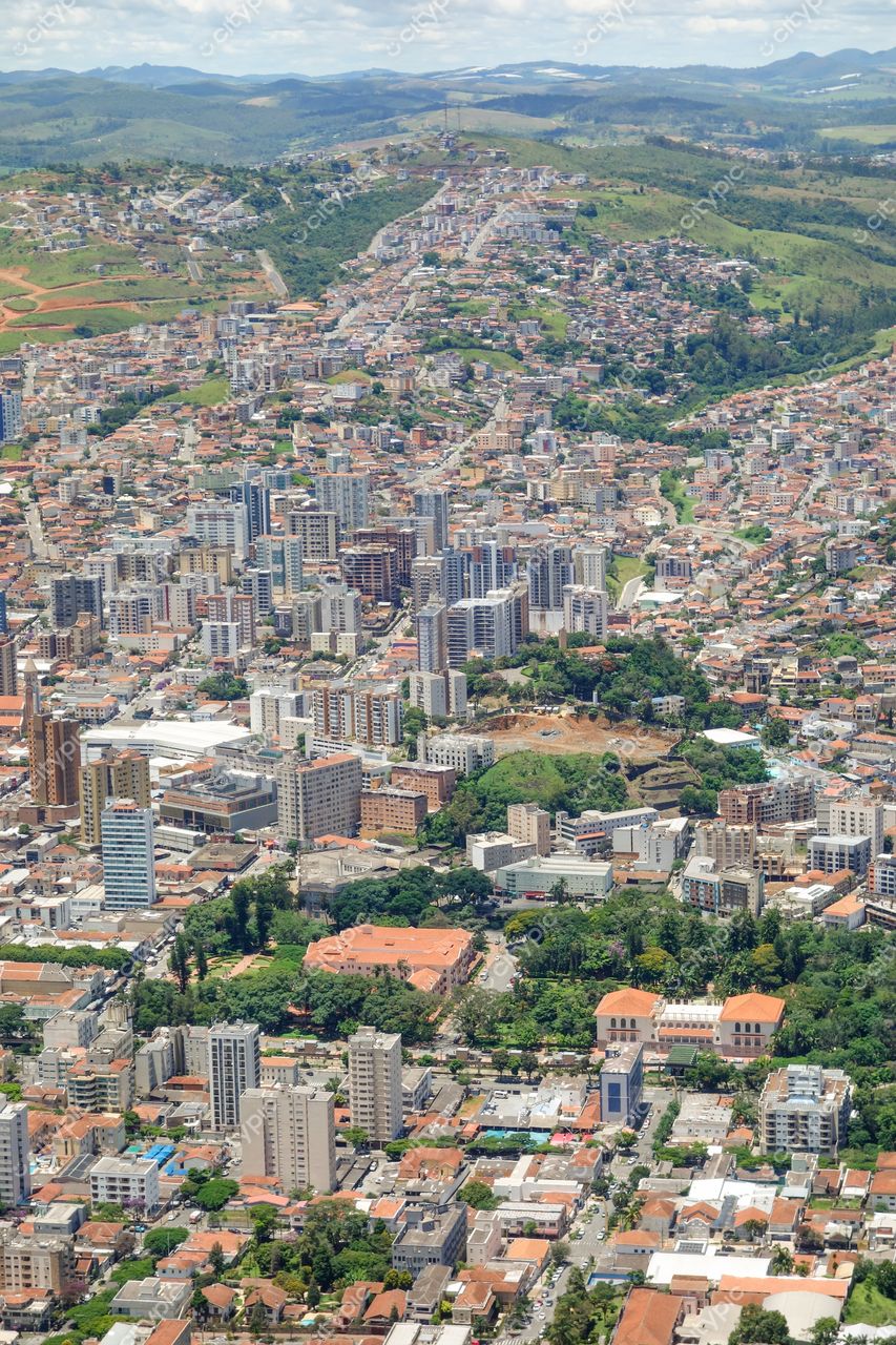 Poços de Caldas, Minas Gerais vista aérea em dia ensolarado com prédios altos e colinas onduladas ao fundo