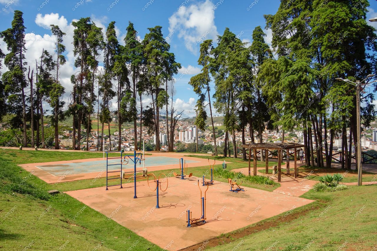 Poços de Caldas, Minas Gerais com parque recreativo e quadra esportiva em dia ensolarado entre colinas e árvores altas