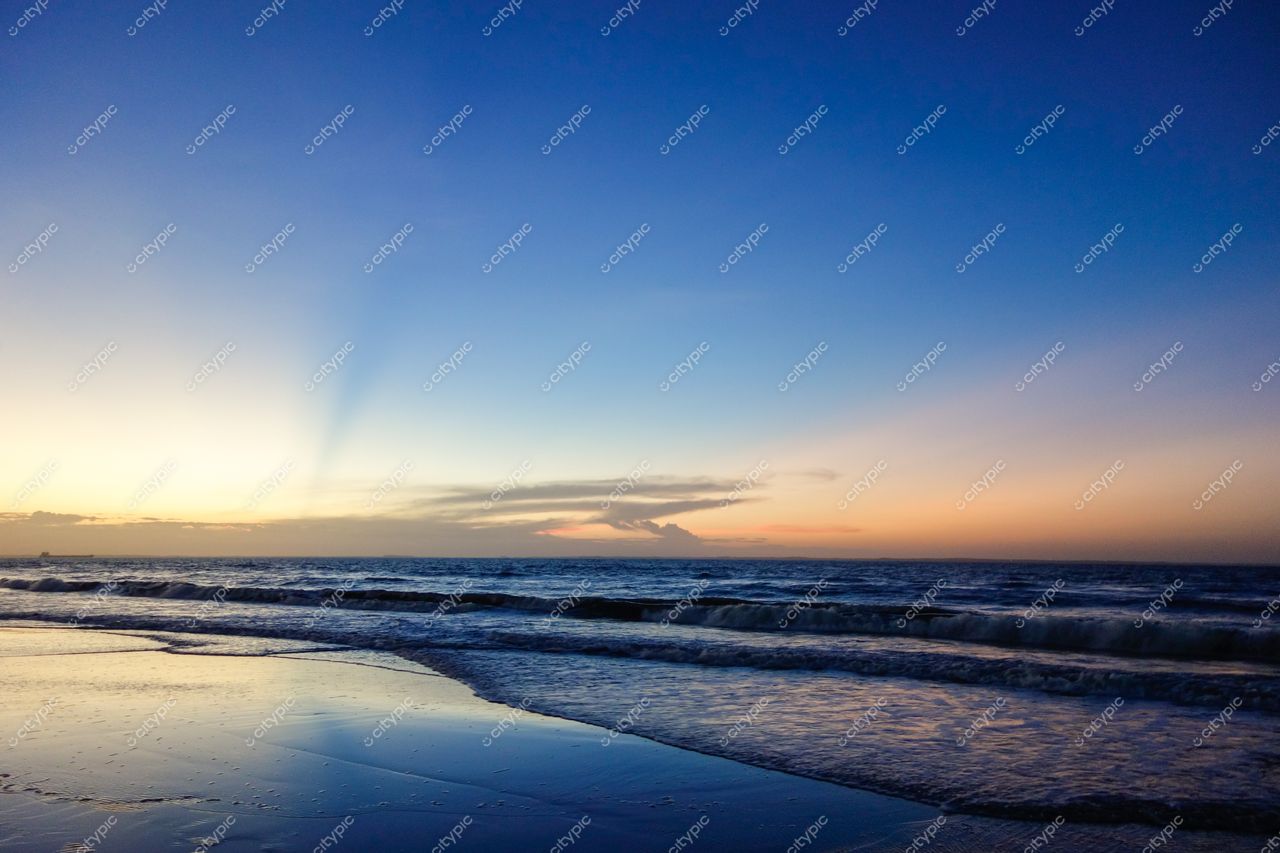 São Luís, Maranhão, crepúsculo na praia com reflexos do céu azul e laranja na areia molhada