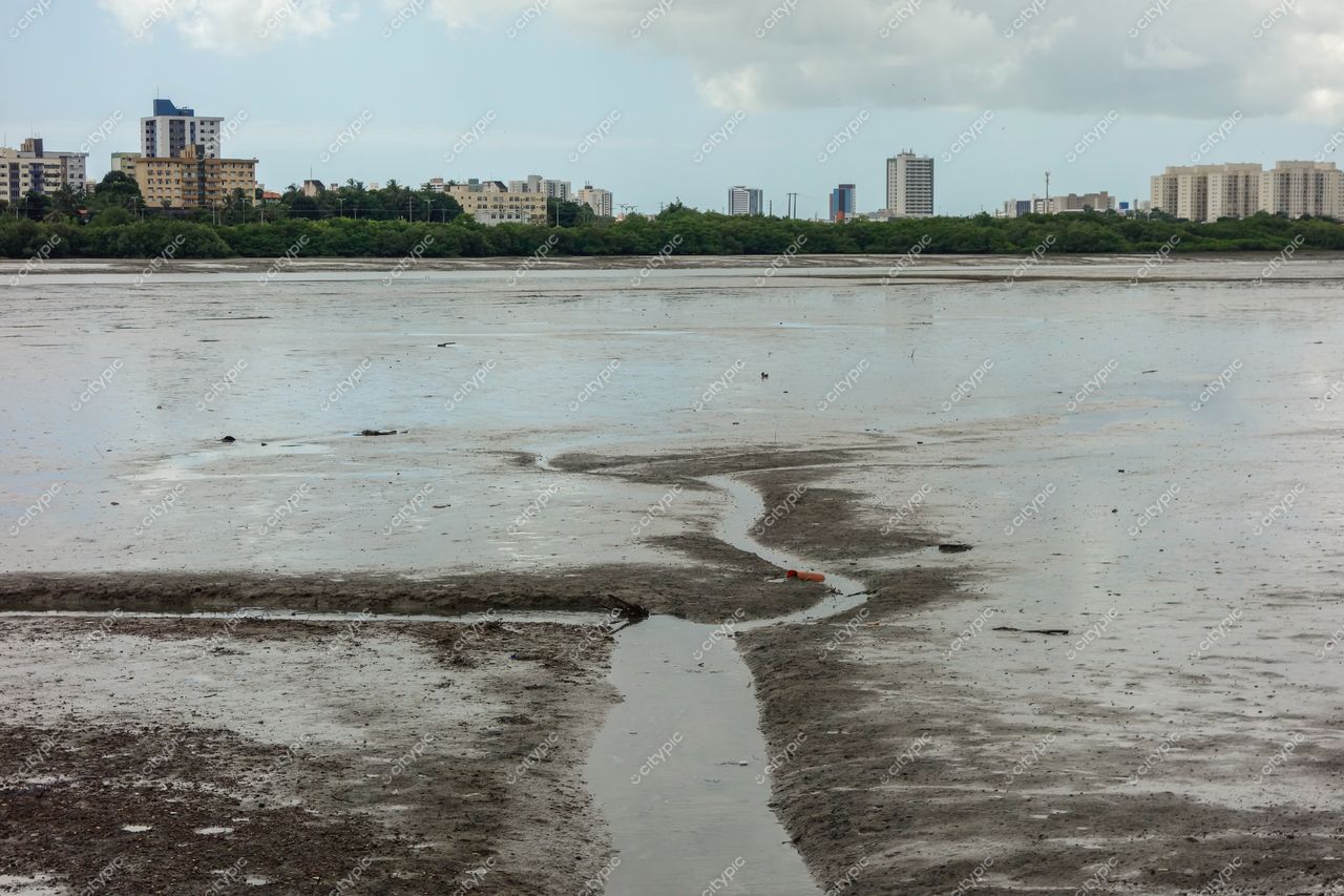 São Luís, Maranhão vista da baía com solo lamacento exposto e edifícios urbanos sob céu parcialmente nublado