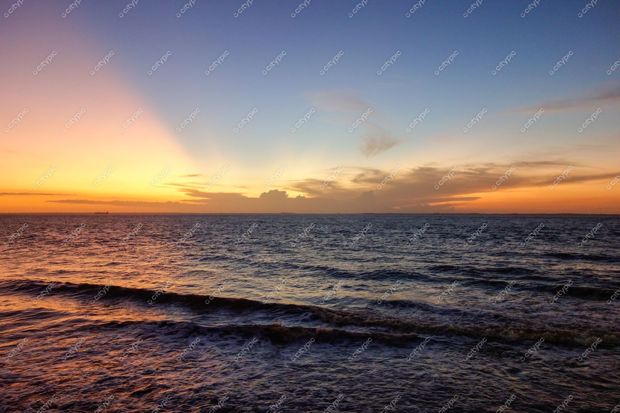 São Luís, Maranhão, pôr do sol sobre o mar com silhueta de navio e ondas suaves refletindo luz quente