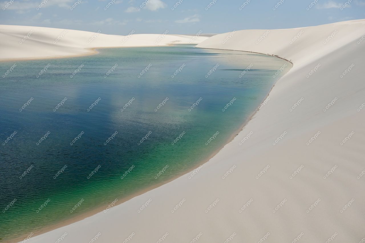 Lençóis Maranhenses, Maranhão, vista das dunas com lago cristalino refletindo céu parcialmente nublado e luz do sol