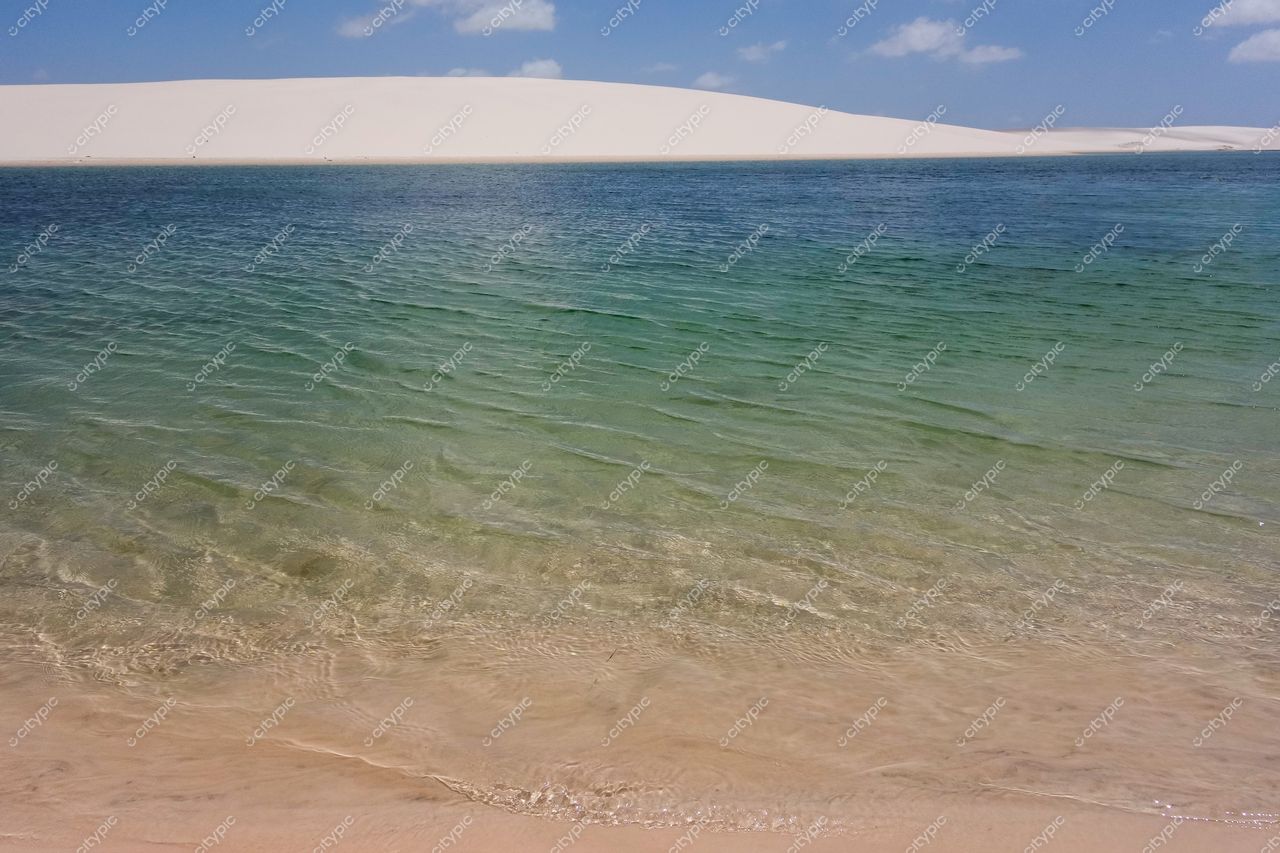 Lençóis Maranhenses, Maranhão com águas cristalinas em tons de azul e verde e dunas brancas sob céu azul claro