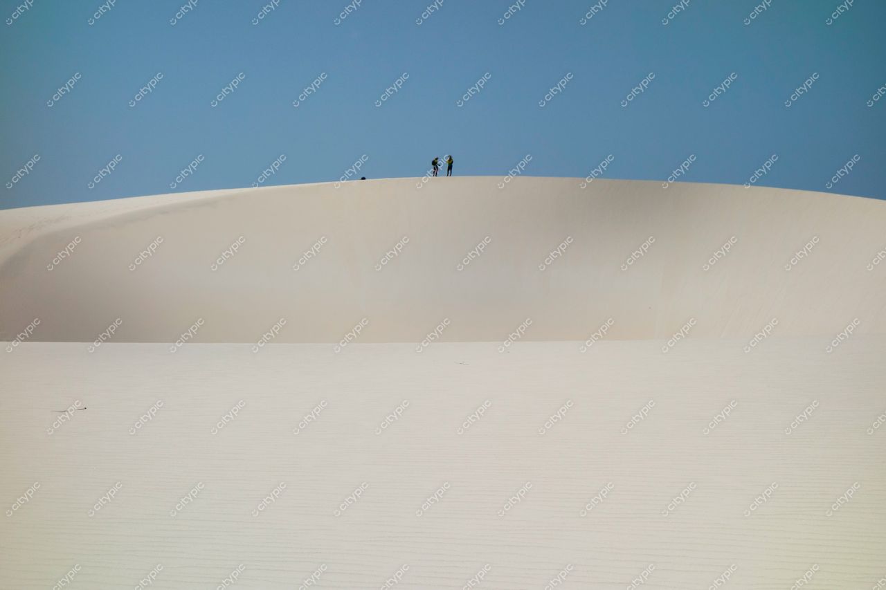 Lençóis Maranhenses, Maranhão, vista das dunas brancas sob céu azul com silhuetas humanas no topo da duna