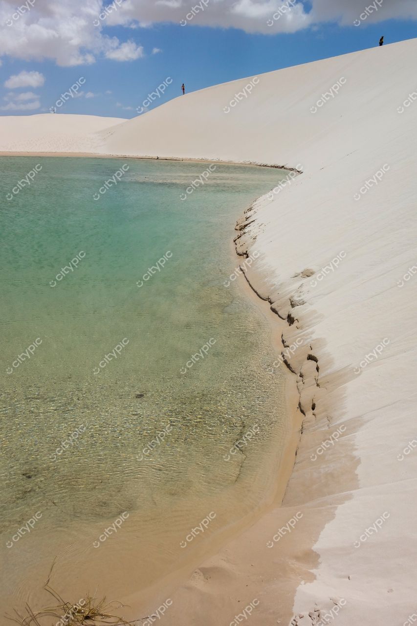 Lençóis Maranhenses, Maranhão, vista das dunas brancas e lagoa cristalina com figuras humanas ao fundo em iluminação suave