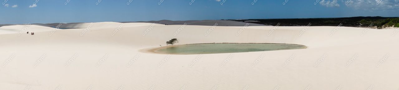 Lençóis Maranhenses, Maranhão, vastas dunas brancas com lago cristalino e vegetação baixa sob céu parcialmente nublado