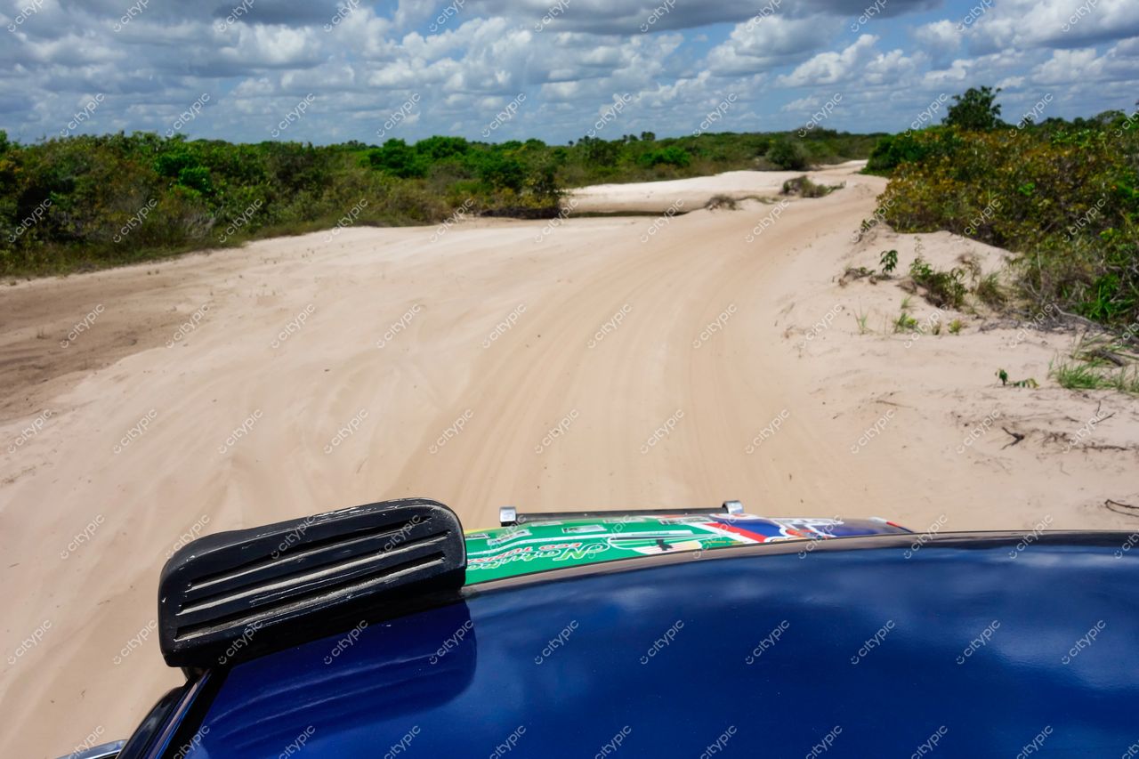 Lençóis Maranhenses, Maranhão, vista do horizonte com carro em caminho de areia sob céu parcialmente nublado