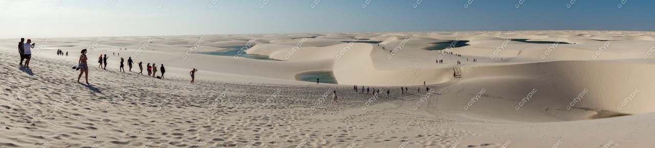 Lençóis Maranhenses, Maranhão, vista panorâmica com pessoas caminhando entre dunas e lagoas sob céu ensolarado