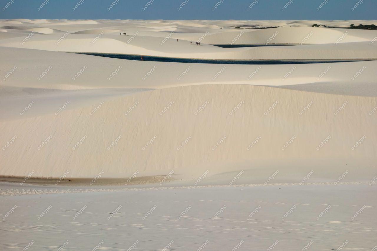 Lençóis Maranhenses, Maranhão, dunas brancas sob céu claro com lagoas azuis e pessoas ao longe para escala