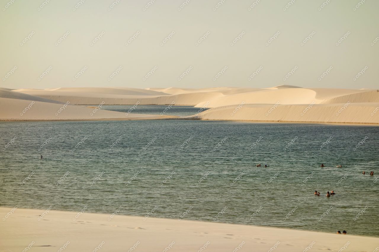 Lençóis Maranhenses, Maranhão, lagoas azuis e verdes cercadas por dunas brancas ao entardecer com pessoas nadando