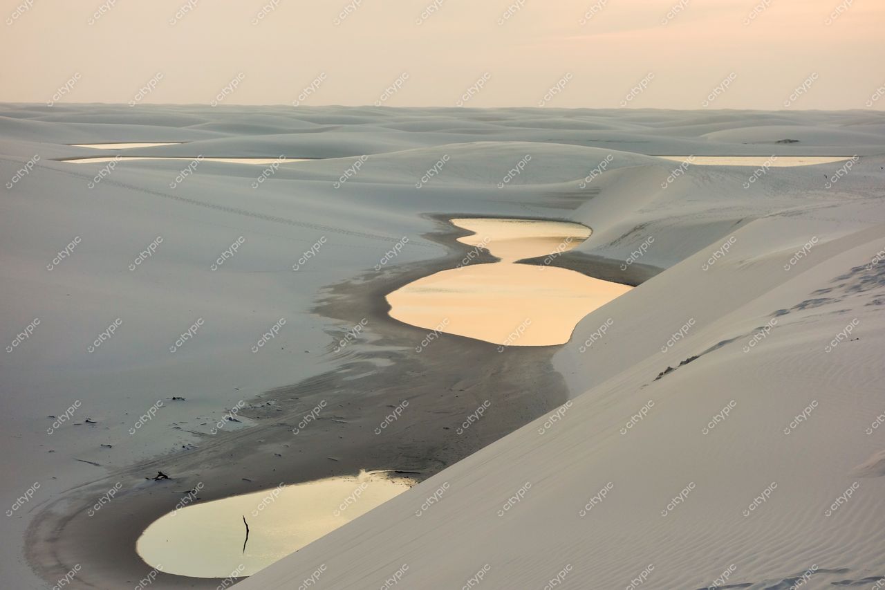 Lençóis Maranhenses, Maranhão, vastas dunas de areia branca e lagoas refletindo a luz suave do entardecer