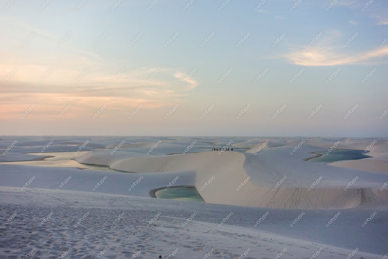 Lençóis Maranhenses, Maranhão, lagoas azuis refletindo o entardecer com pessoas apreciando as dunas de areia branca