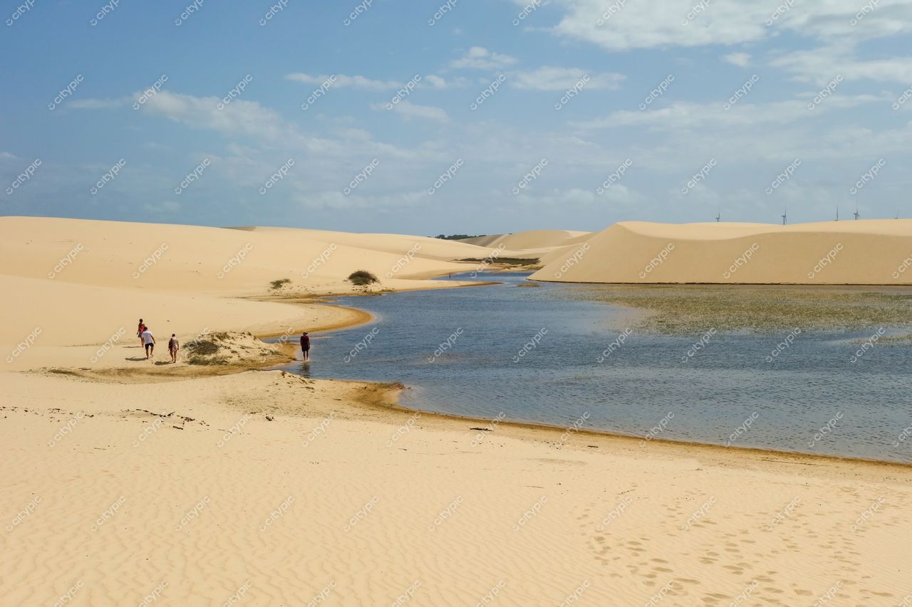Atins, Maranhão, dunas de areia e água doce com pessoas explorando a margem em dia ensolarado