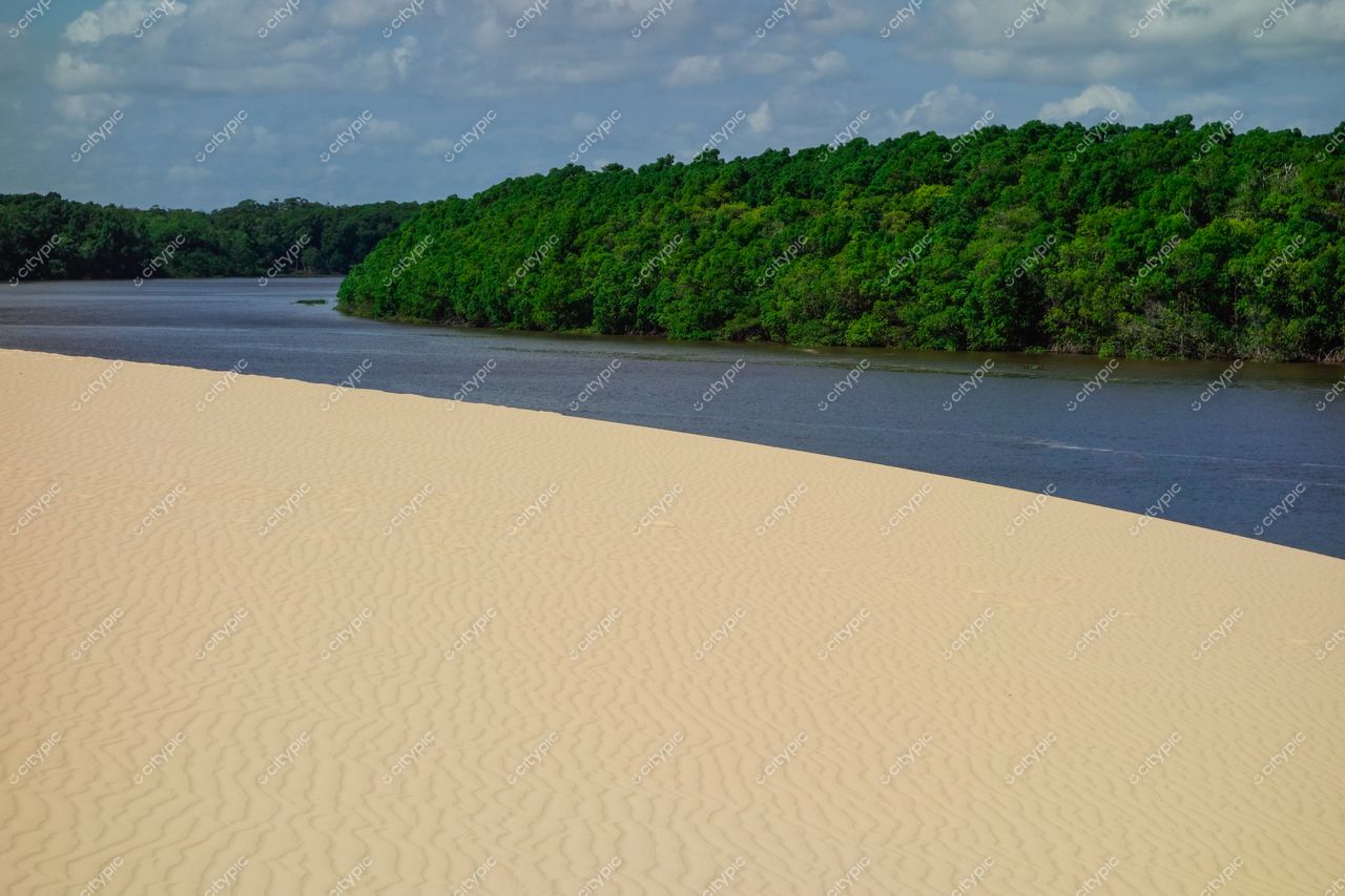 Atins, Maranhão vista serena com faixa de areia clara à esquerda e rio calmo à direita em dia claro