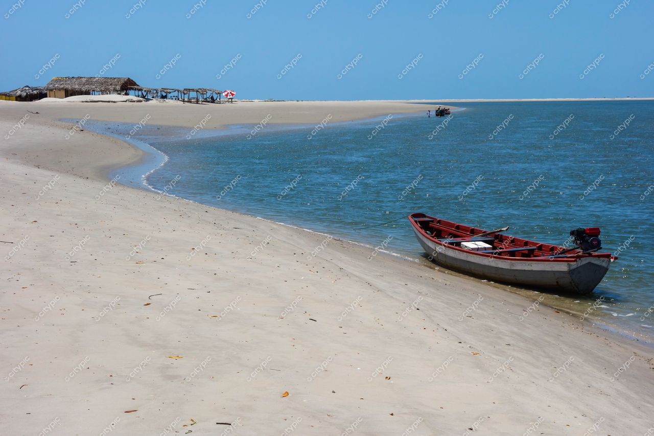 Atins, Maranhão, praia de areia clara com barco de pesca ancorado e construções simples ao fundo em dia ensolarado