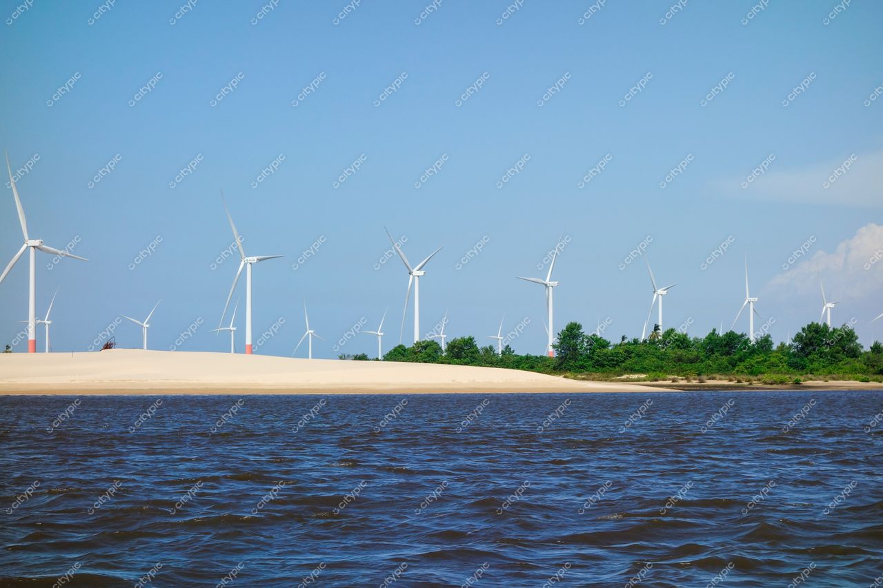 Atins, Maranhão campo de turbinas eólicas ao fundo com água refletindo luz do dia e vegetação verde