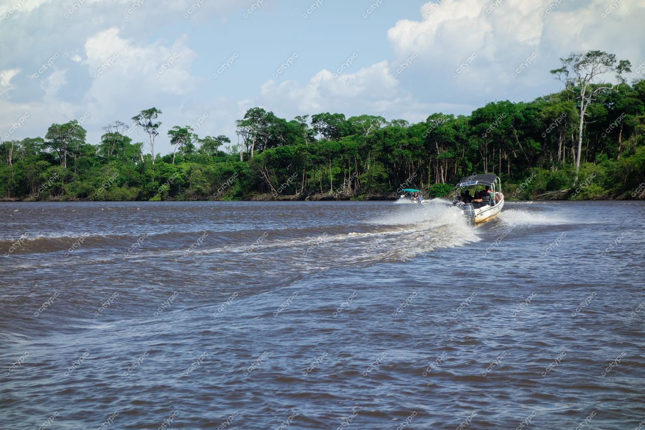 Atins, Maranhão, barcos navegando em rio com vegetação densa ao fundo e céu parcialmente nublado durante o dia