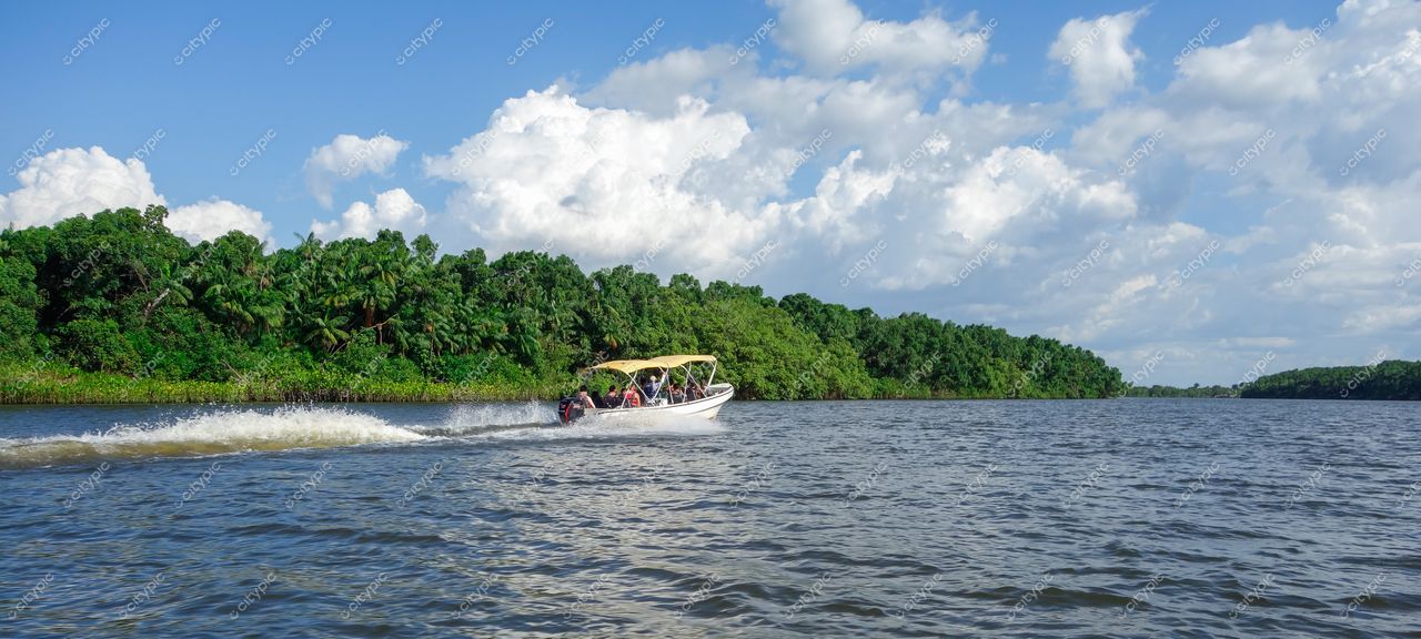 Atins, Maranhão lancha navega em águas tranquilas cercada por vegetação tropical sob céu azul e nuvens brancas