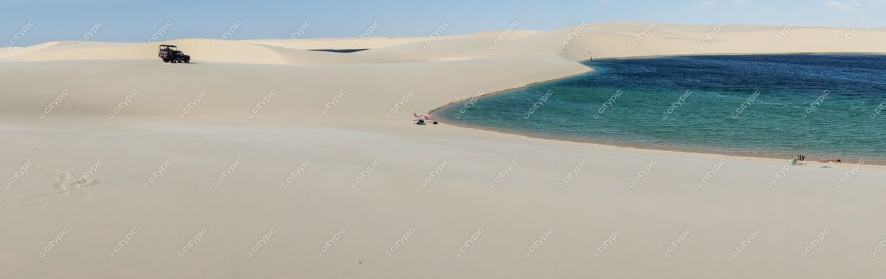 Lençóis Maranhenses, Maranhão, vastas dunas de areia clara com veículo 4×4 e pessoas próximas a corpo d’água azul