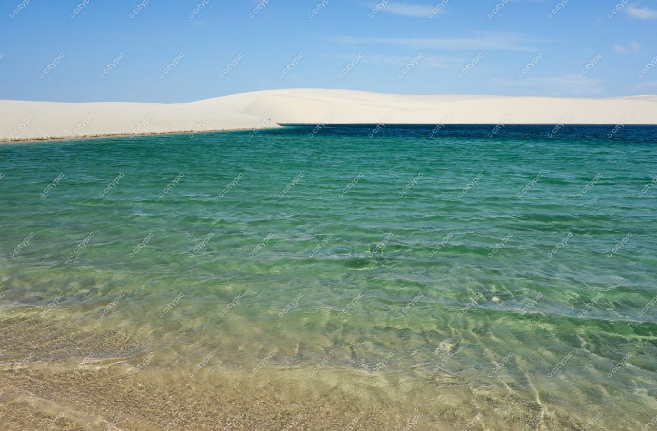Lençóis Maranhenses, Maranhão, águas cristalinas em tons de verde e azul contrastando com dunas brancas sob céu ensolarado