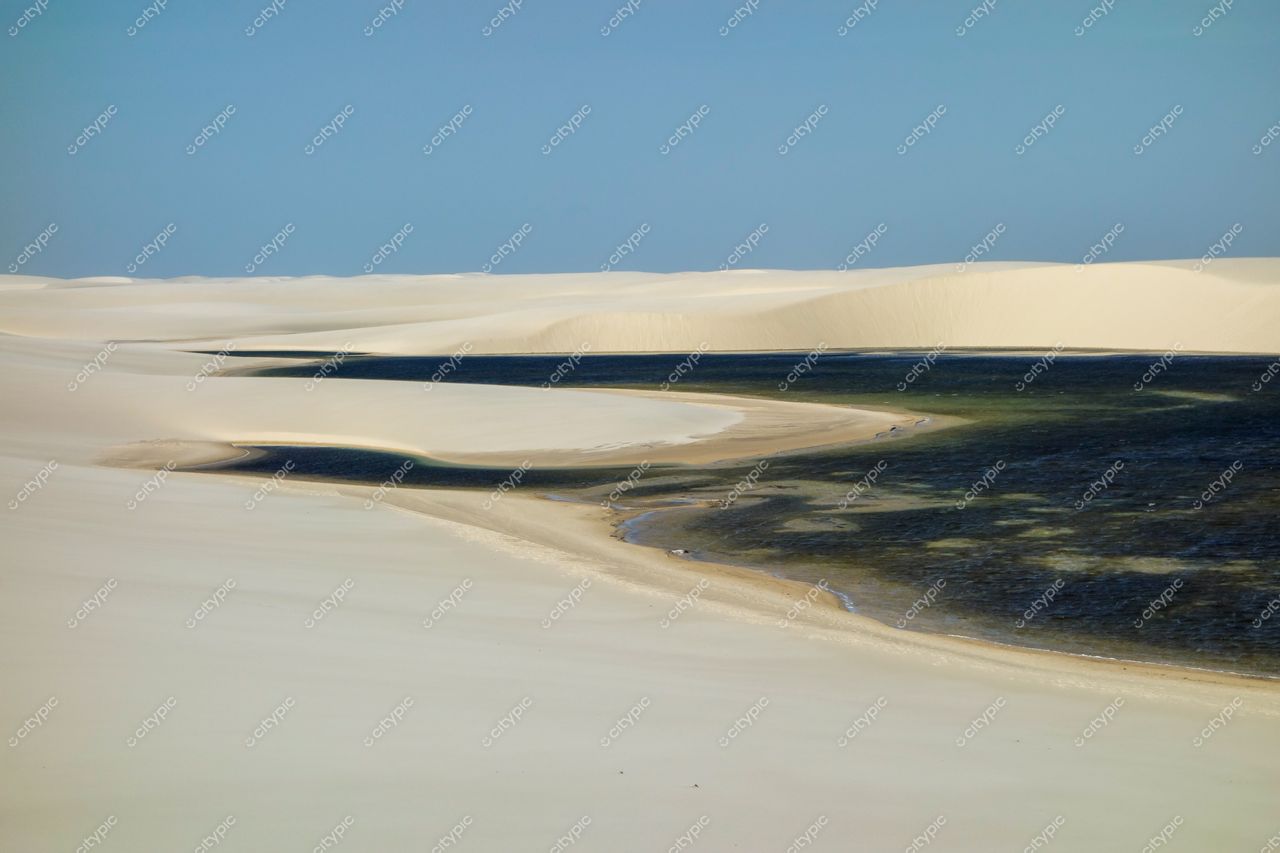 Lençóis Maranhenses, Maranhão, vista panorâmica das dunas brancas com vegetação esparsa e lagoa refletindo tons de azul