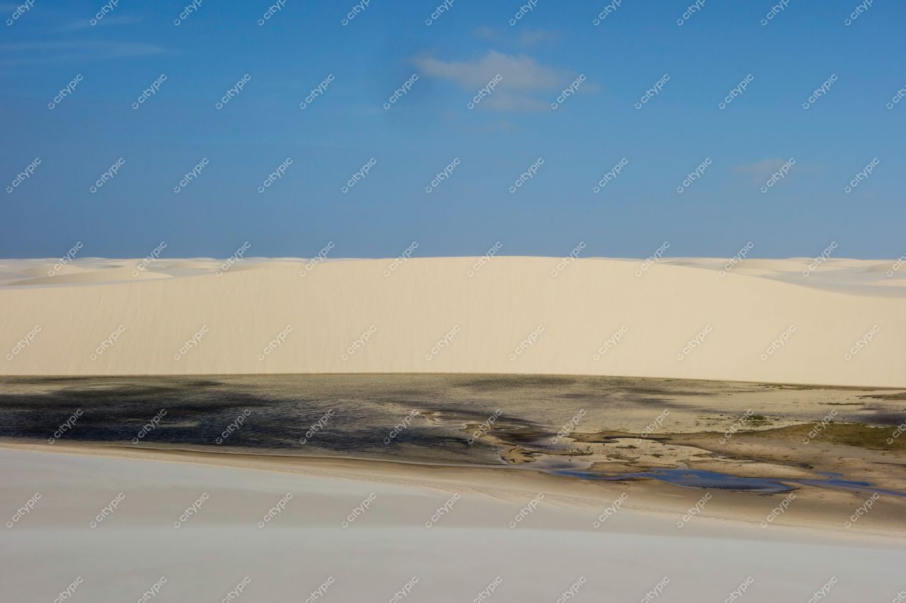 Lençóis Maranhenses, Maranhão, vastas dunas brancas sob céu azul com nuvens e corpos d’água contrastantes ao fundo