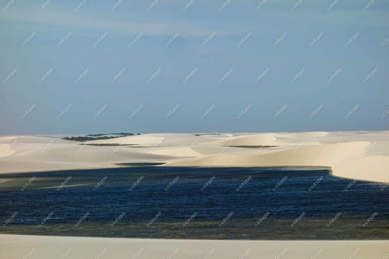 Lençóis Maranhenses, Maranhão, vista das dunas brancas com lençol d’água azul sob céu claro e vegetação esparsa