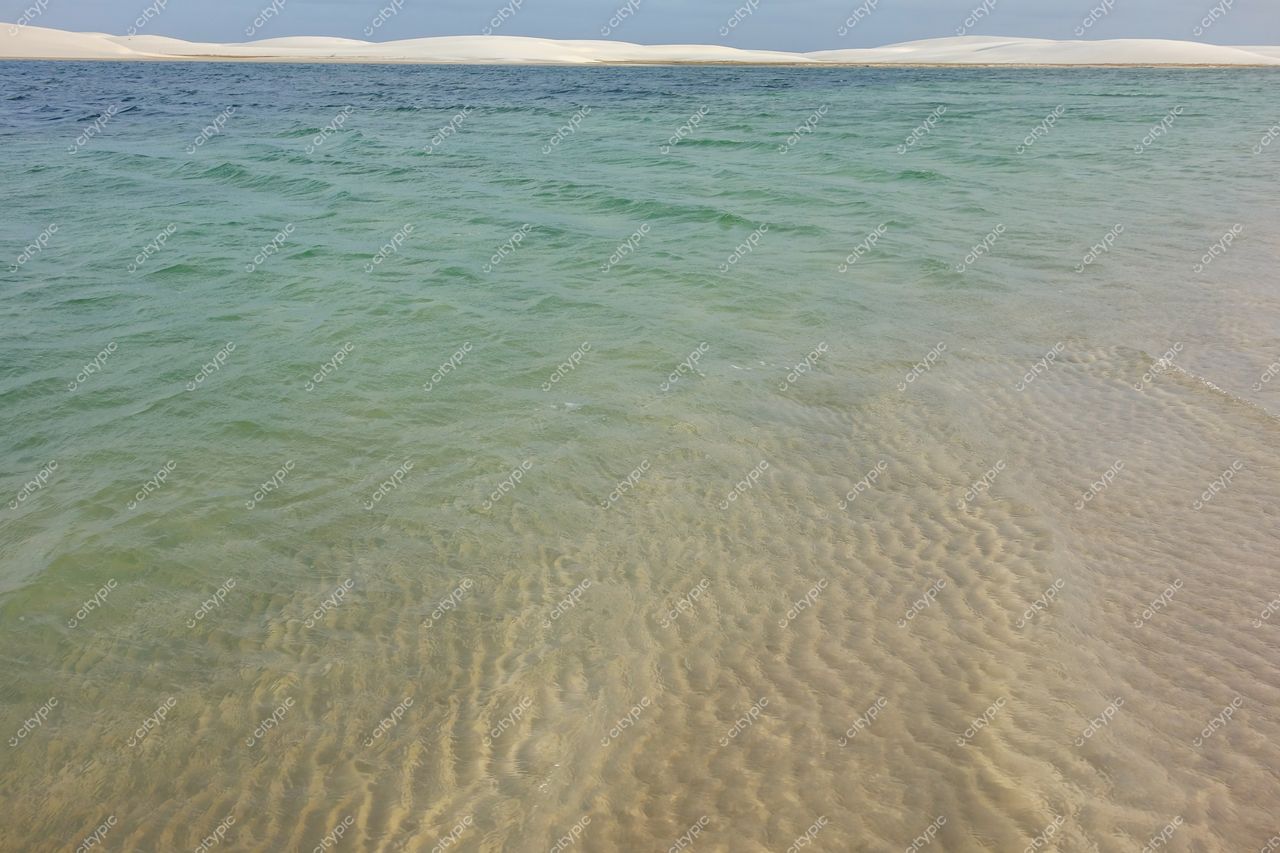 Lençóis Maranhenses, Maranhão, transição entre águas cristalinas e areia clara com dunas brancas sob céu nublado