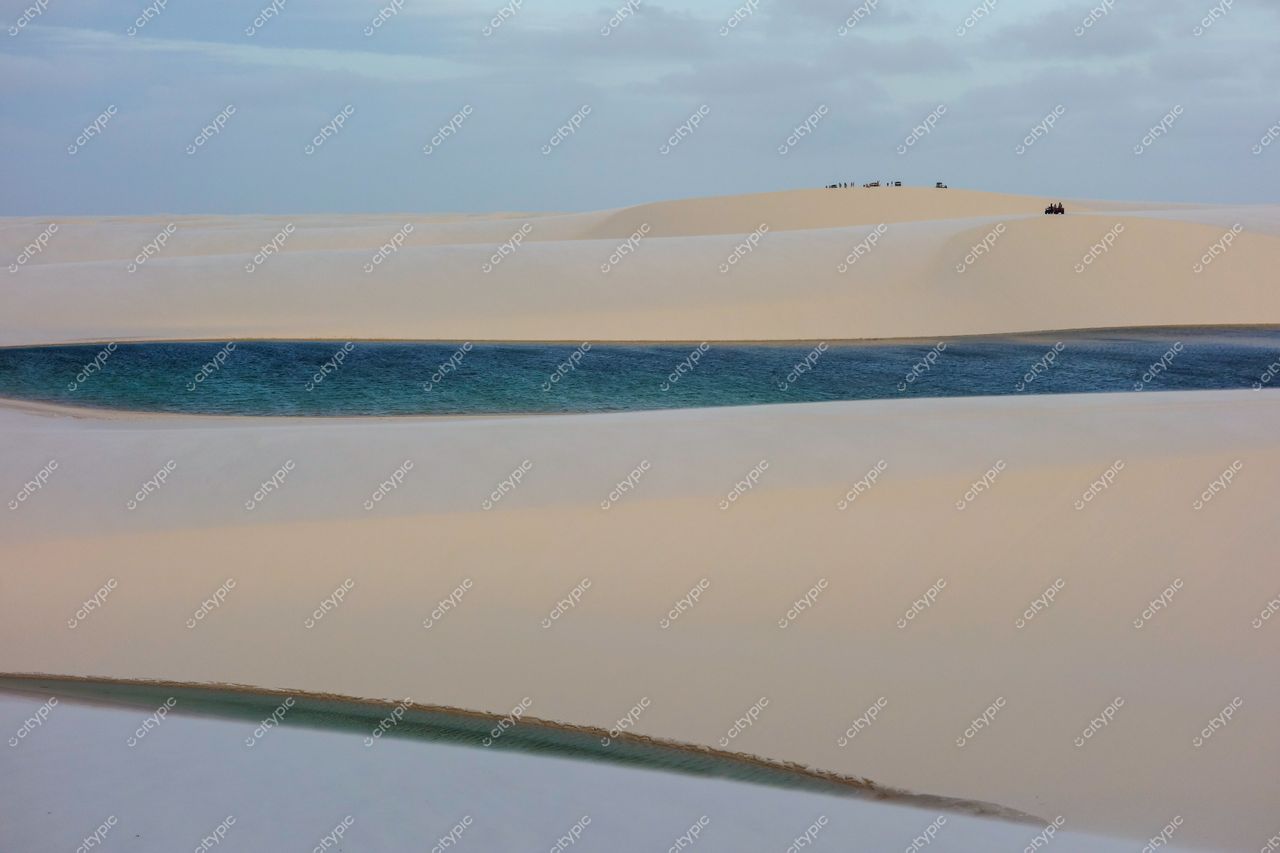 Lençóis Maranhenses, Maranhão, lagoa azul-emeraldina cercada por dunas brancas sob céu nublado ao entardecer