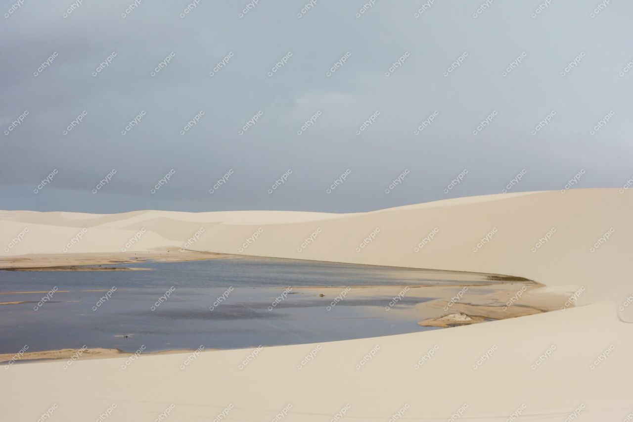 Lençóis Maranhenses, Maranhão vista serena com montanhas de areia branca e lagoas azuladas sob céu nublado