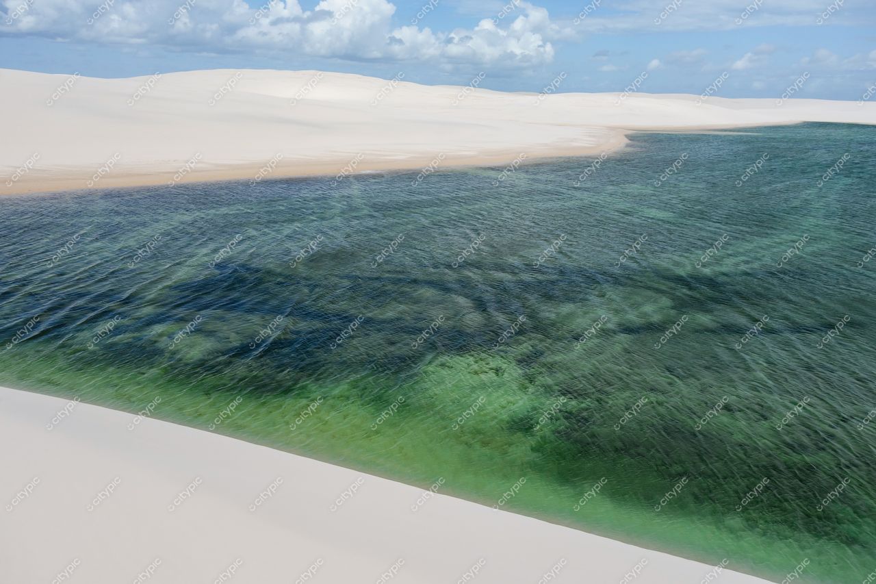 Lençóis Maranhenses, Maranhão, lagoas azuladas refletindo céu nublado entre dunas brancas e vegetação rala ao redor