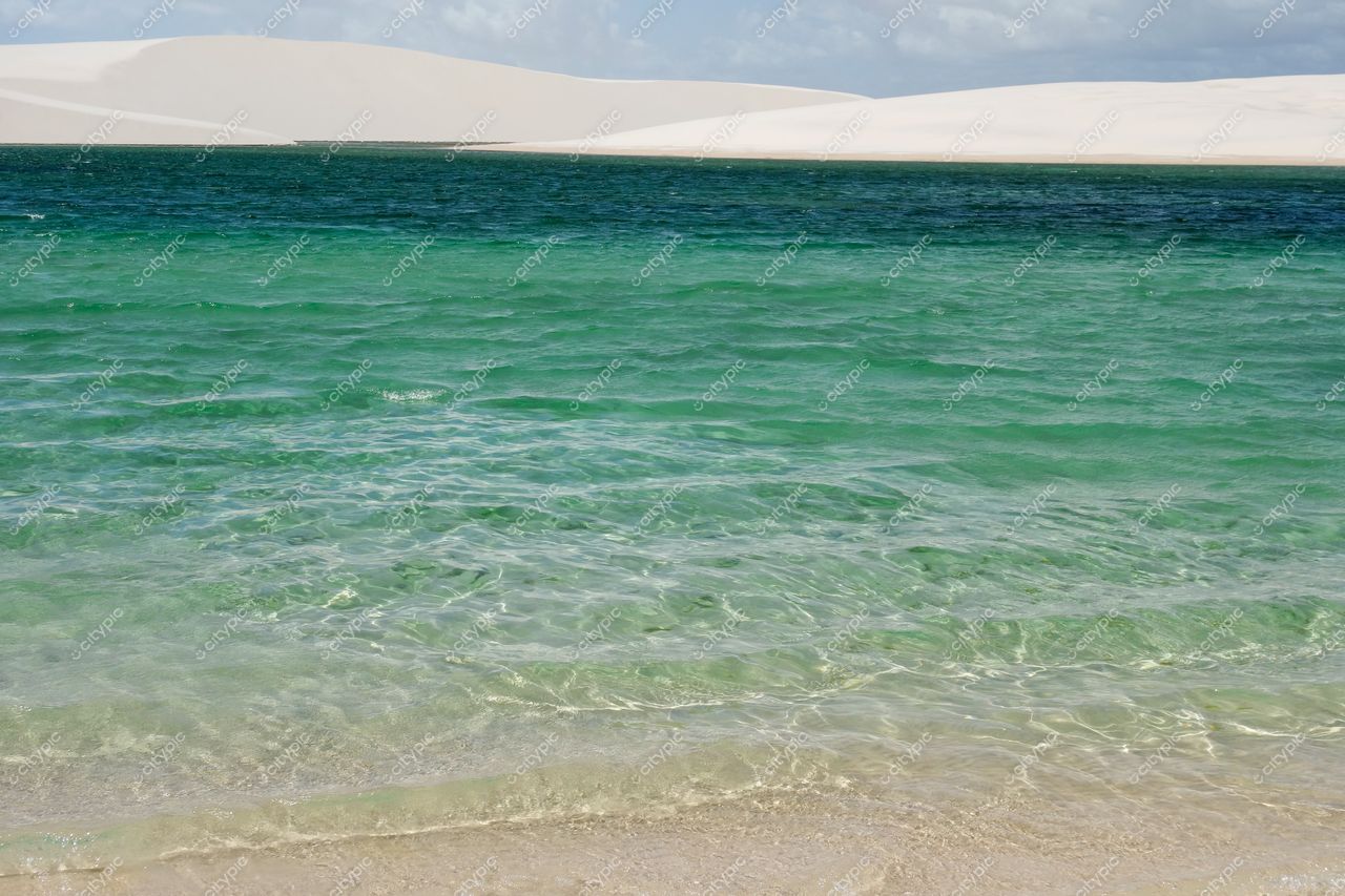 Lençóis Maranhenses, Maranhão, paisagem com águas cristalinas em tons de verde e azul sob céu claro e dunas brancas