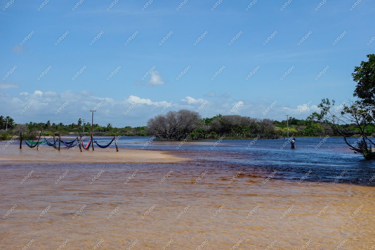 Santo Amaro do Maranhão, Maranhão, encontro de águas sob céu azul com redes de descanso e vegetação típica