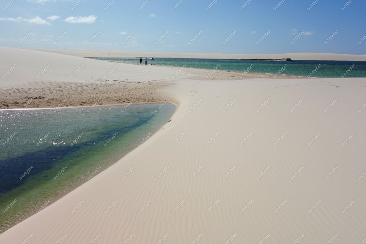Lençóis Maranhenses, Maranhão, visitantes caminhando perto de lagoas azul-turquesa em dia ensolarado com dunas brancas