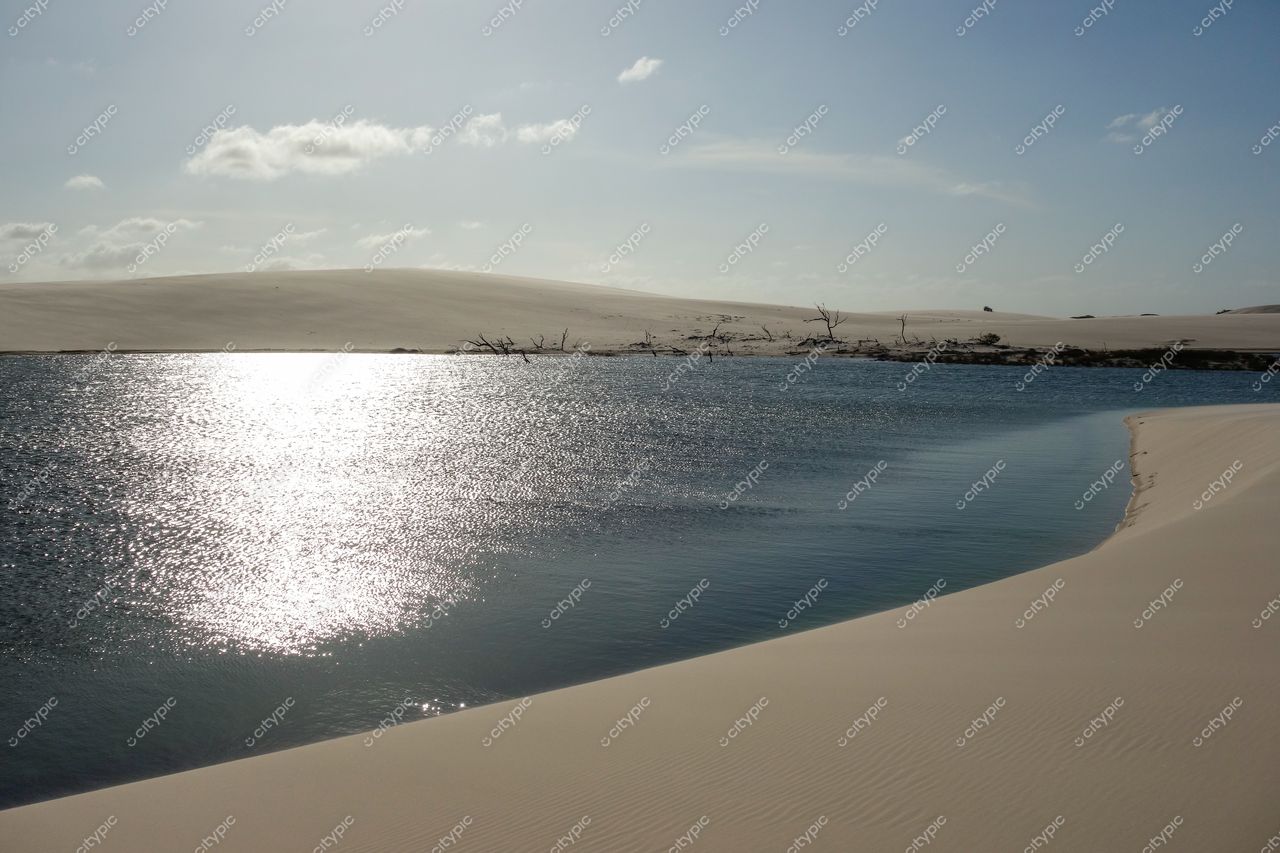 Lençóis Maranhenses, Maranhão, lagoa tranquila refletindo dunas de areia clara sob luz suave em dia nublado