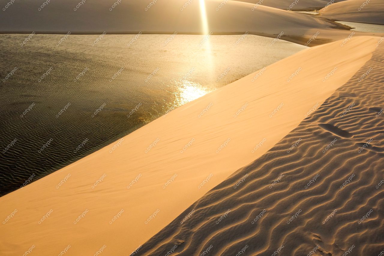 Lençóis Maranhenses, Maranhão, duna clara ao entardecer com espelho d’água e céu em tonalidades quentes