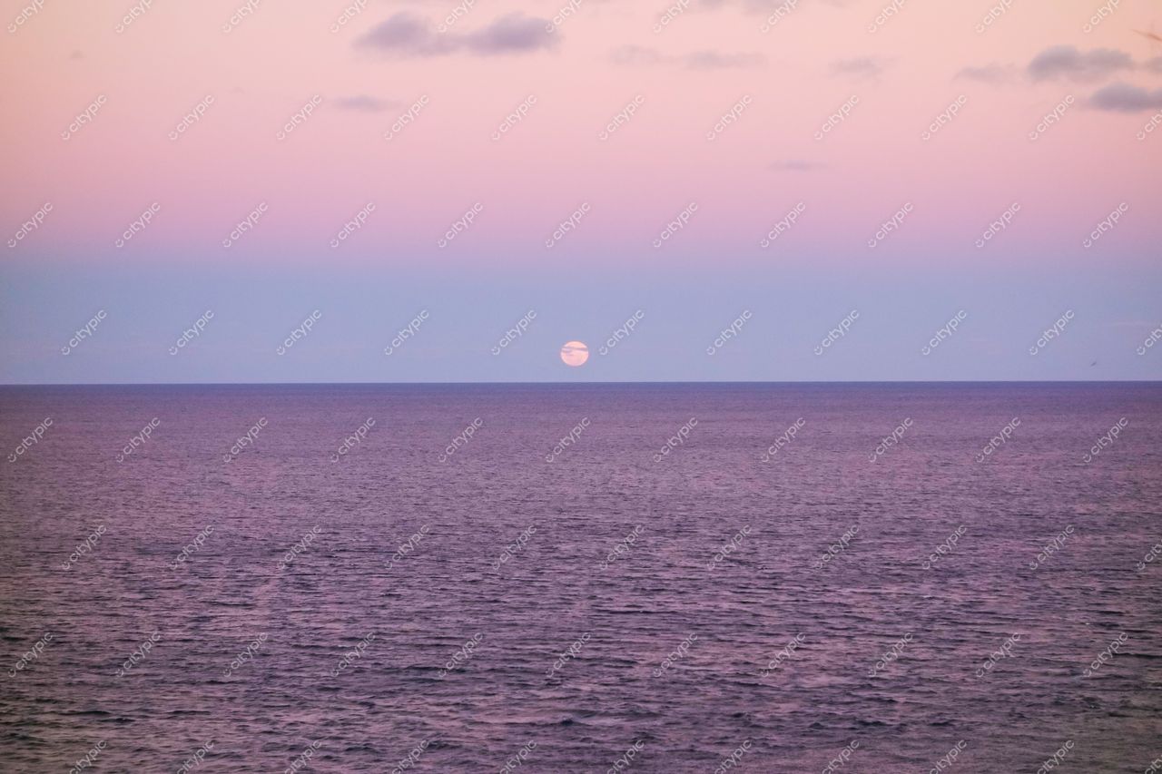 Morro de São Paulo, Bahia ao amanhecer com mar calmo refletindo tons suaves e lua visível no céu