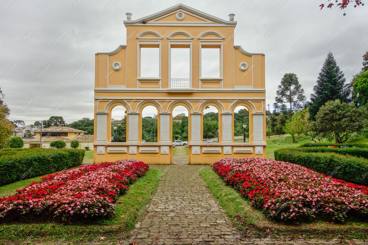 Curitiba, Paraná arquitetura neoclássica amarela com arcos em dia nublado e jardim bem cuidado ao fundo urbano