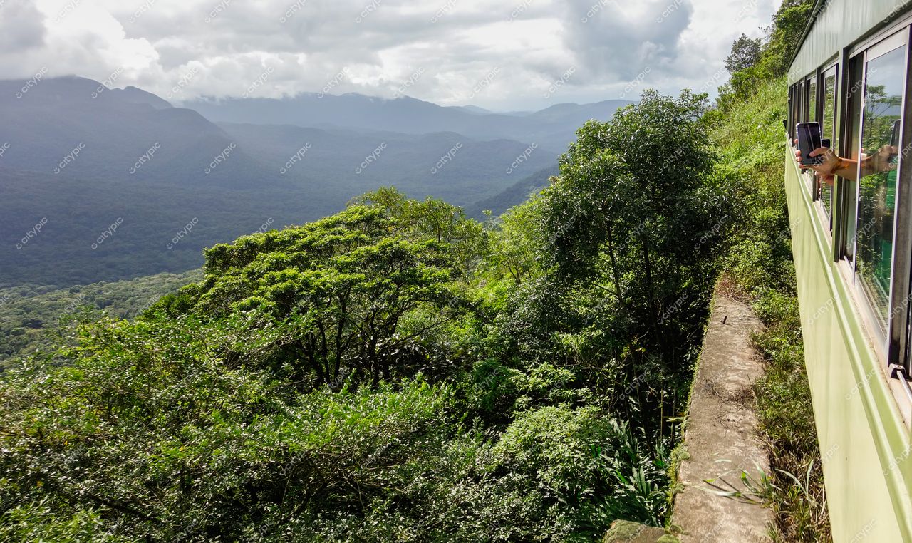 Morretes, Paraná vista panorâmica com trem colorido e mão segurando smartphone em dia nublado e vegetação densa