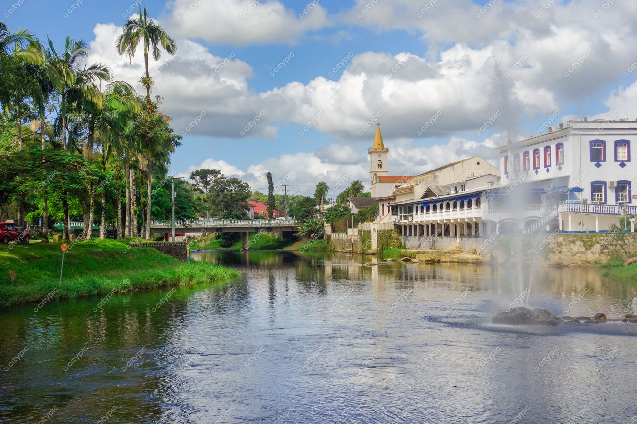 Morretes, Paraná vista do centro com rio refletindo vegetação e céu nublado, edifícios históricos e chafariz