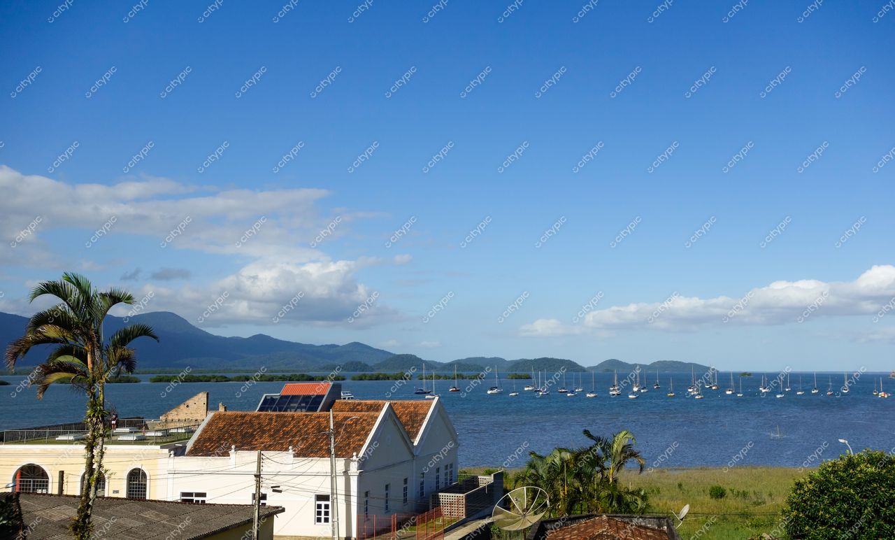 Antonina, Paraná vista panorâmica em dia ensolarado com construção branca, baía de barcos e montanhas ao fundo