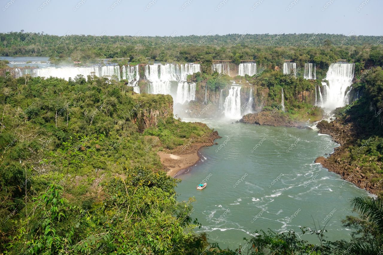 Foz do Iguaçu, Paraná, dia claro com vegetação densa e barco no rio em frente às Cataratas do Iguaçu